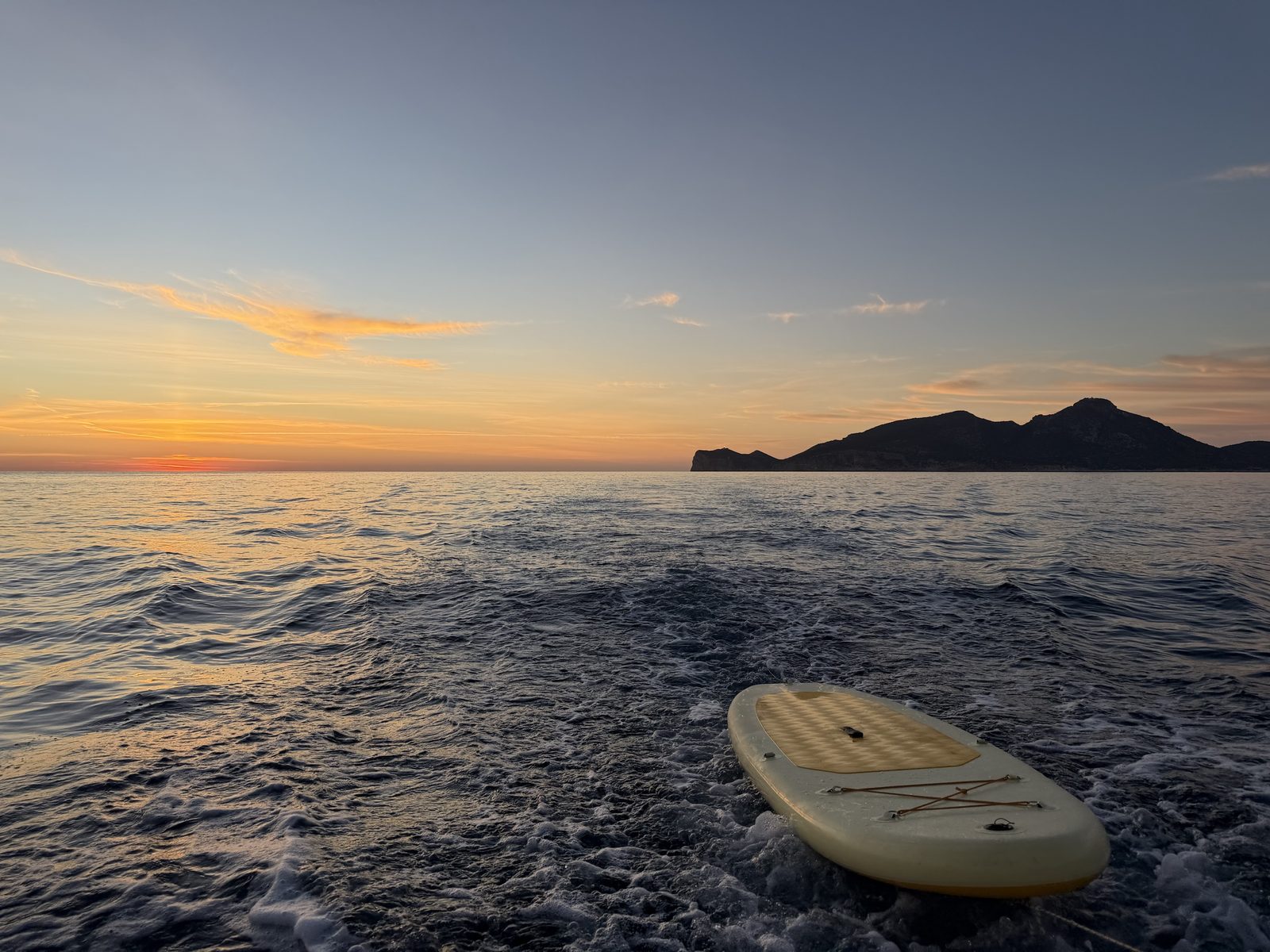 A paddleboard on the sea at sunset, an island on the horizon